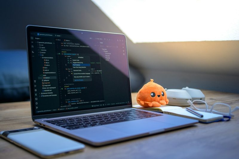 Laptop dengan tampilan kode di meja kerja developer